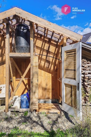 A wooden structure with a metal tank, a door, and a small porch area.