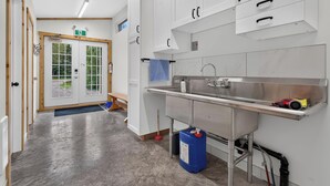 Eine saubere, moderne Küche mit Edelstahlgeräten, einem Spülbecken und einem blauen Behälter für Reinigungsmittel.