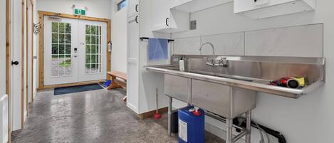 A clean, modern kitchen with stainless steel appliances, a sink, and a blue cleaning supply container.
