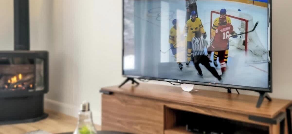 Een televisie bevestigd aan een houten standaard, met een open haard op de achtergrond.