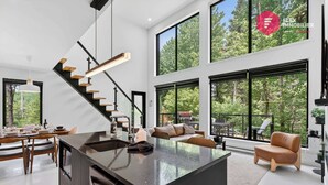 Ein modernes Interieur mit Kücheninsel, Essbereich und einer Treppe zu einer oberen Ebene.