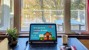 Una computadora portátil sobre una mesa mostrando un mensaje en francés sobre el alquiler de una cabaña.