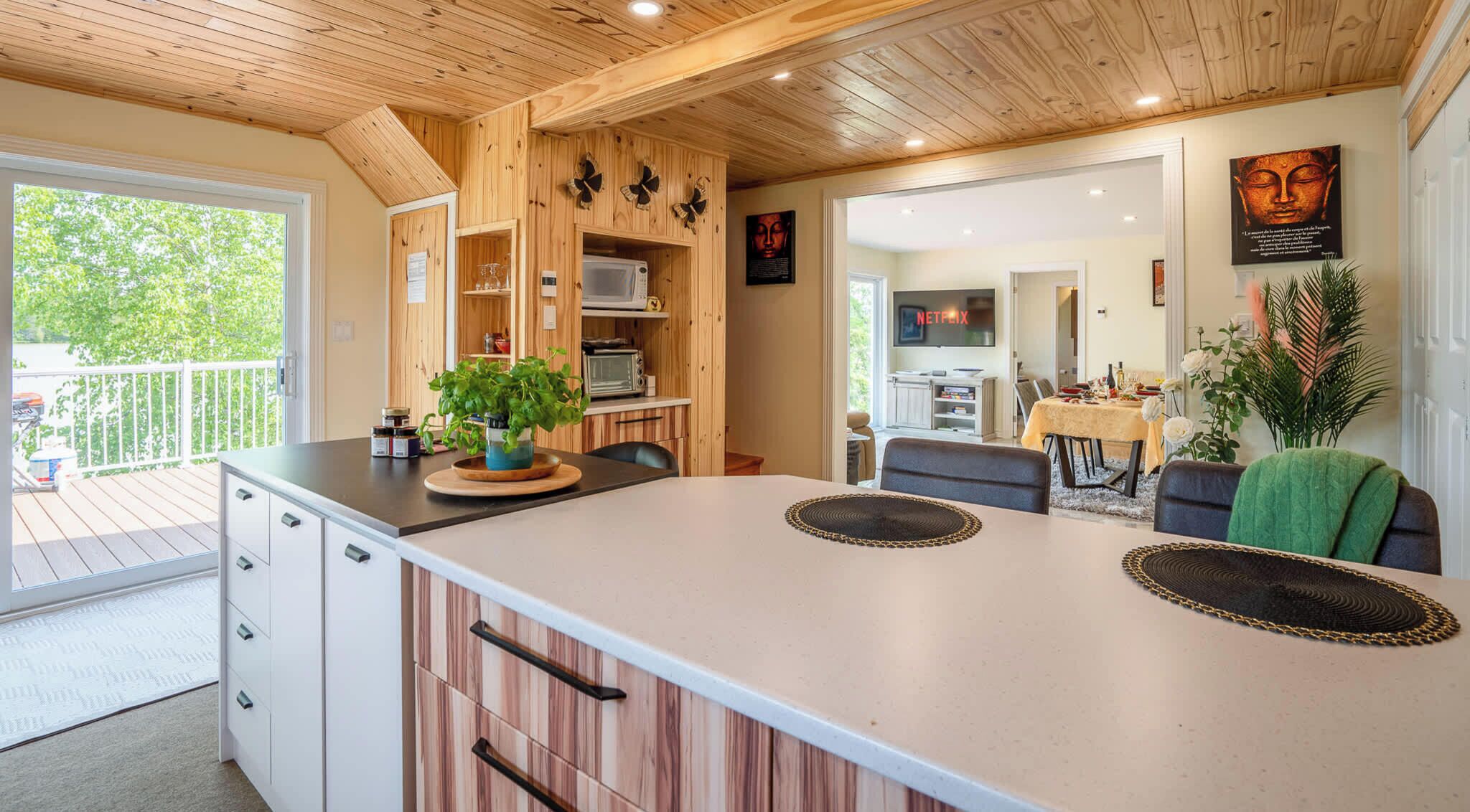 Een moderne keuken met houten kastjes, een centraal eiland en een eetgedeelte met tafel en stoelen.