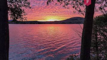 A sunset over a lake with trees framing the view.