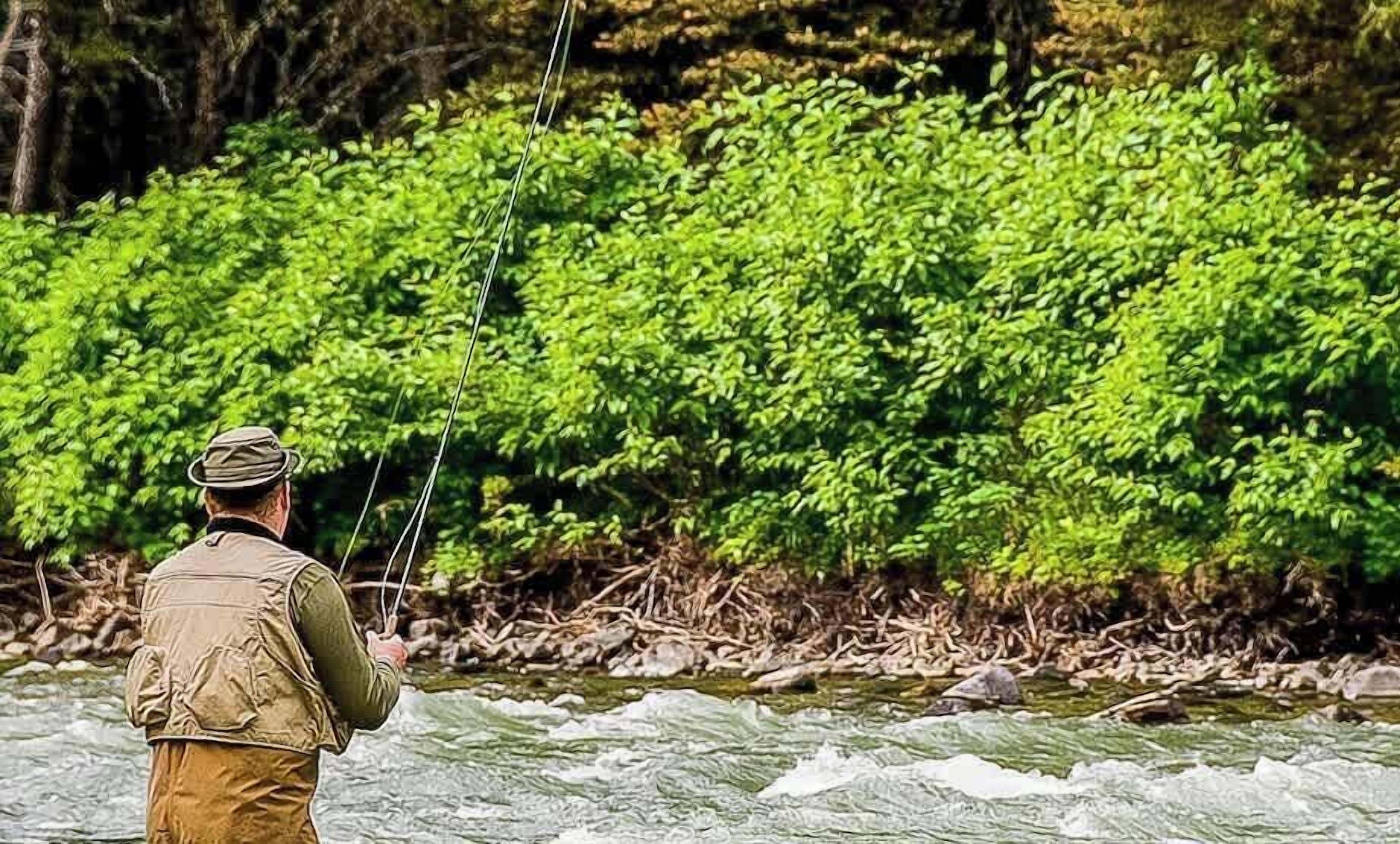 Una persona de pie en un río, sosteniendo cañas de pescar.