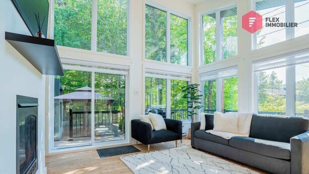 Un salón amplio con ventanas grandes, una chimenea y un sofá moderno.