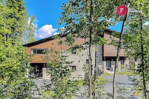 A modern building with a stone facade, a wooden roof, and a gravel driveway.