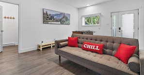 A living room with a sofa, a painting, a window, and a door.