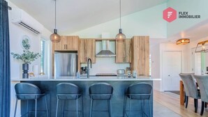 Een moderne keuken met houten kastjes, een roestvrijstalen koelkast en een bar met drie krukken.