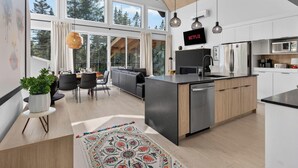 A modern kitchen with a central island, built-in appliances, and a dining area with a view of the outdoors.