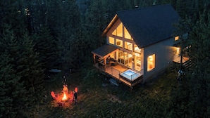 A two-story cabin with a deck and a fire pit area.