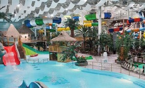 Parque acuático interior con toboganes, piscinas y estructuras con temática tropical.