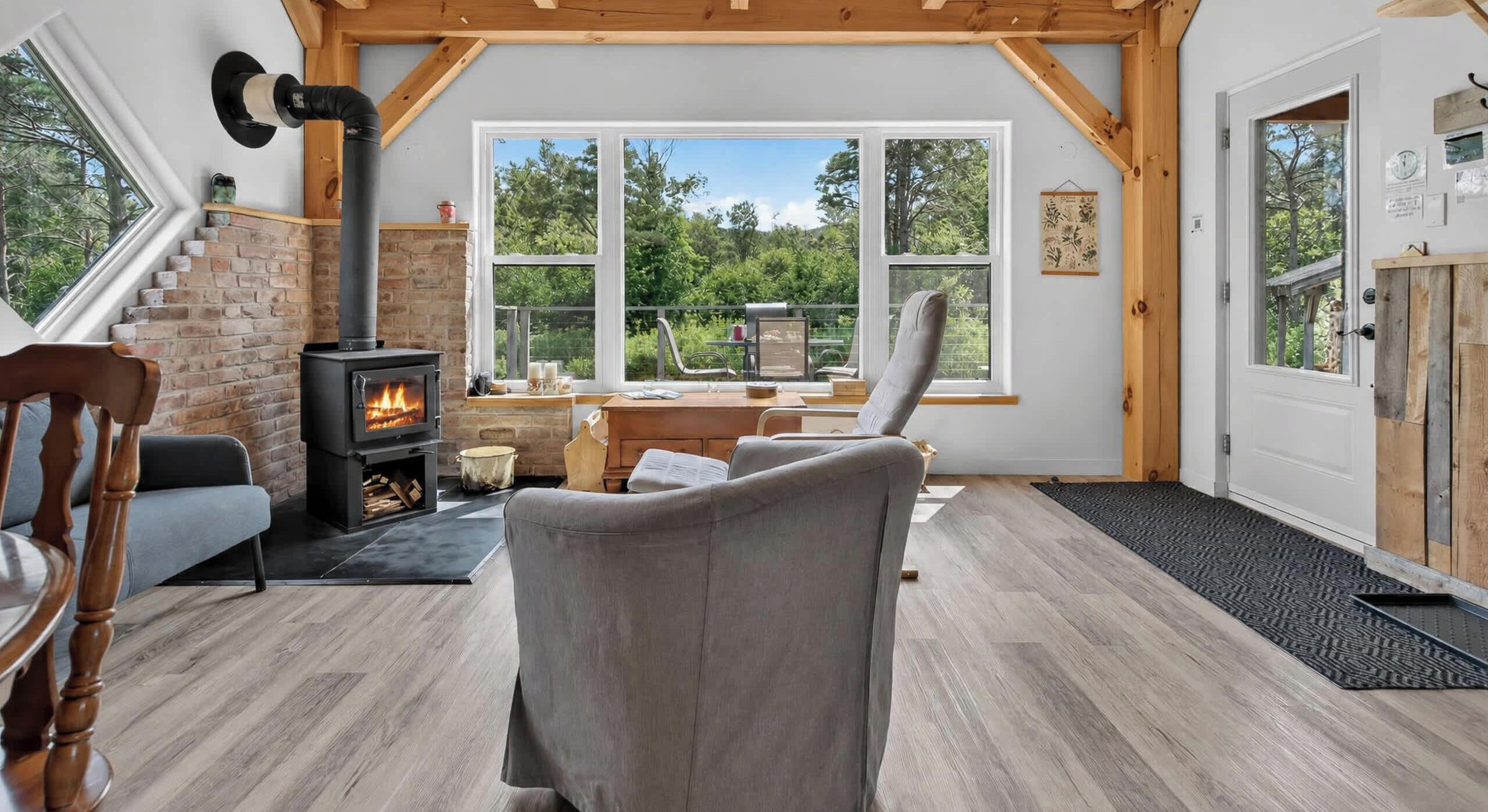 Une pièce confortable avec une cheminée, un canapé, un bureau et une vue sur l’extérieur.