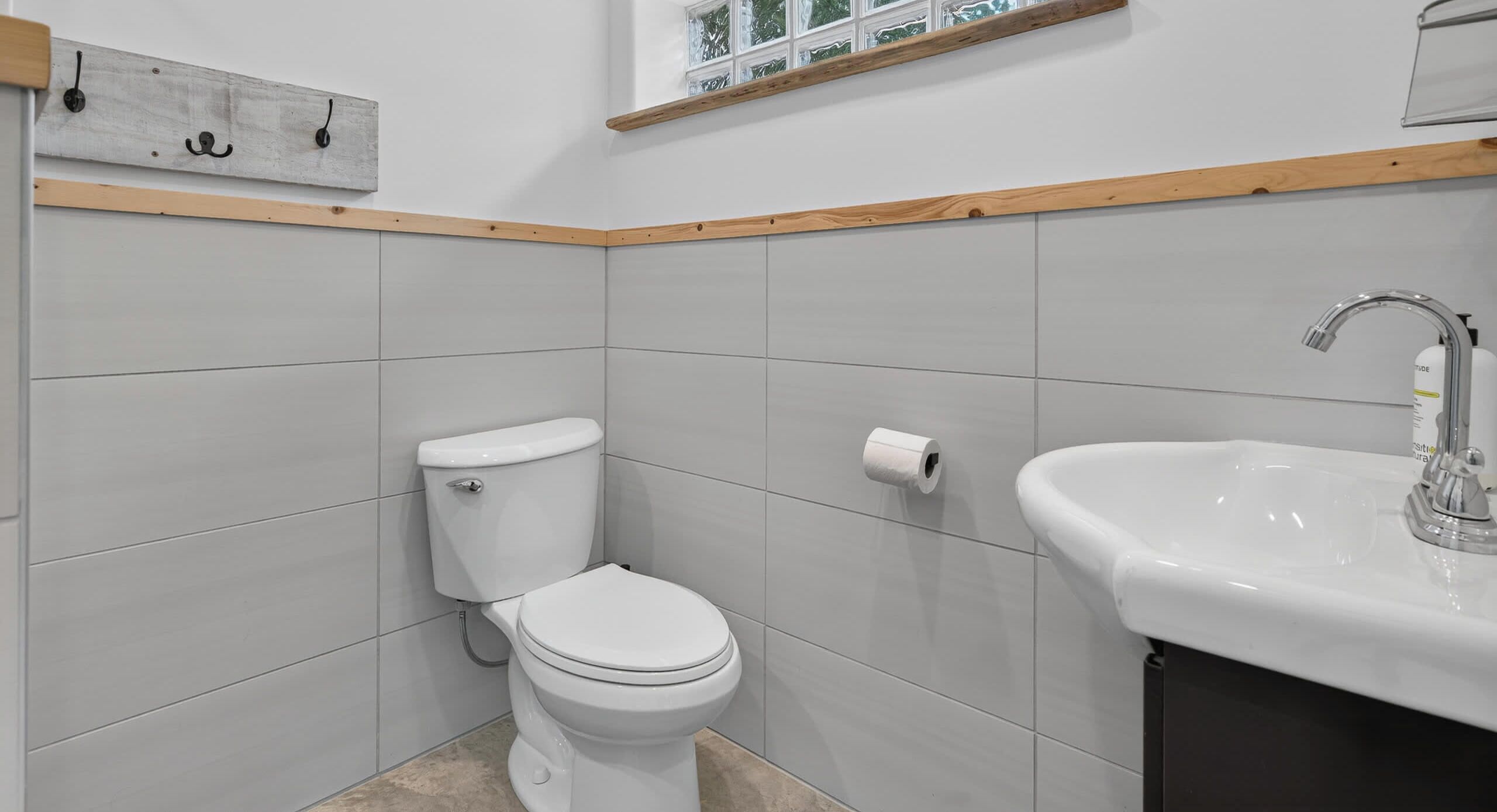 A bathroom with a toilet, a sink, and a window above the sink.