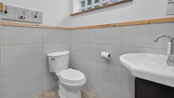 A bathroom with a toilet, a sink, and a window above the sink.