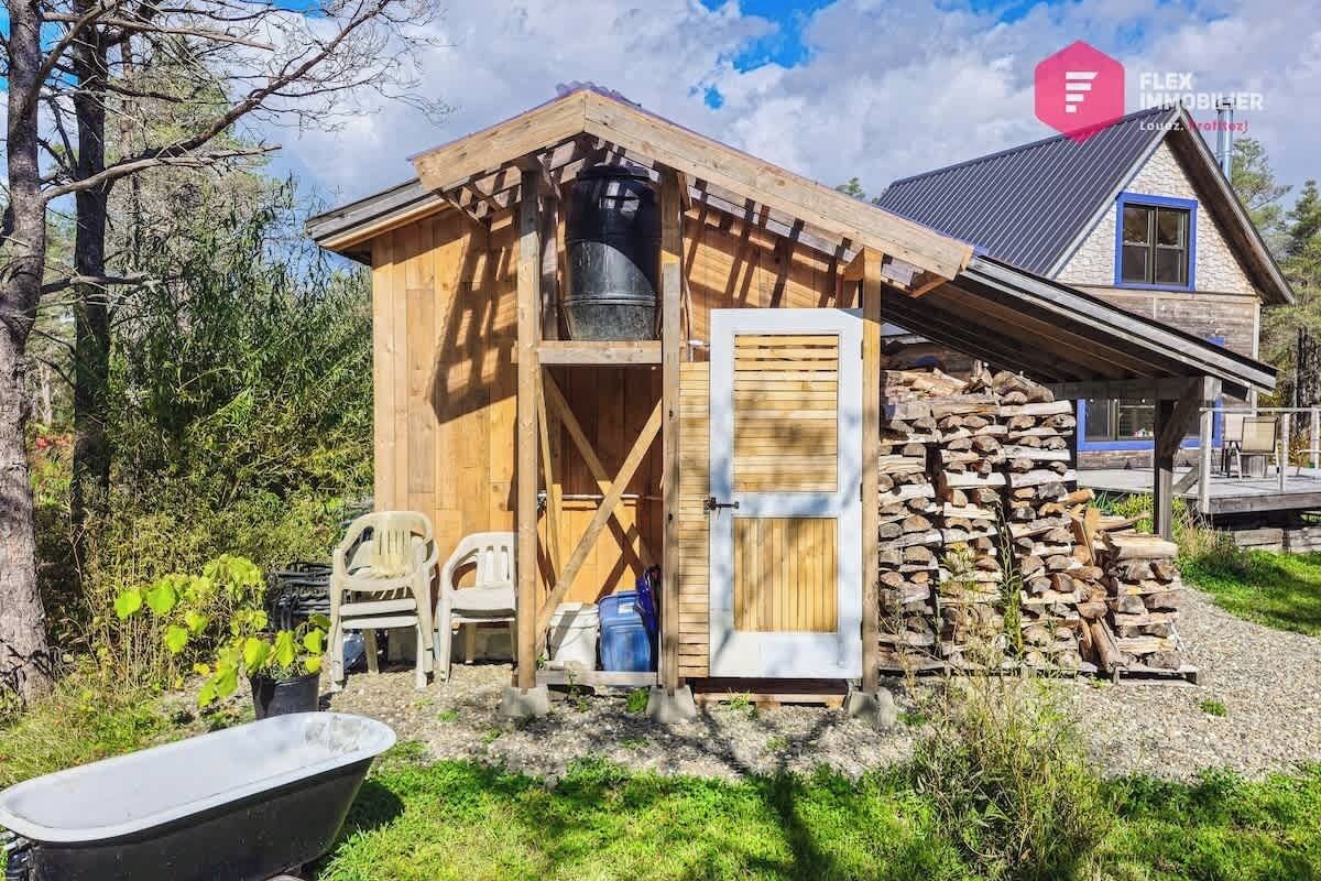 A wooden cabin with a stone wall, a door, and a window.
