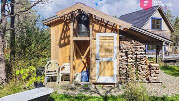 A wooden cabin with a stone wall, a door, and a window.