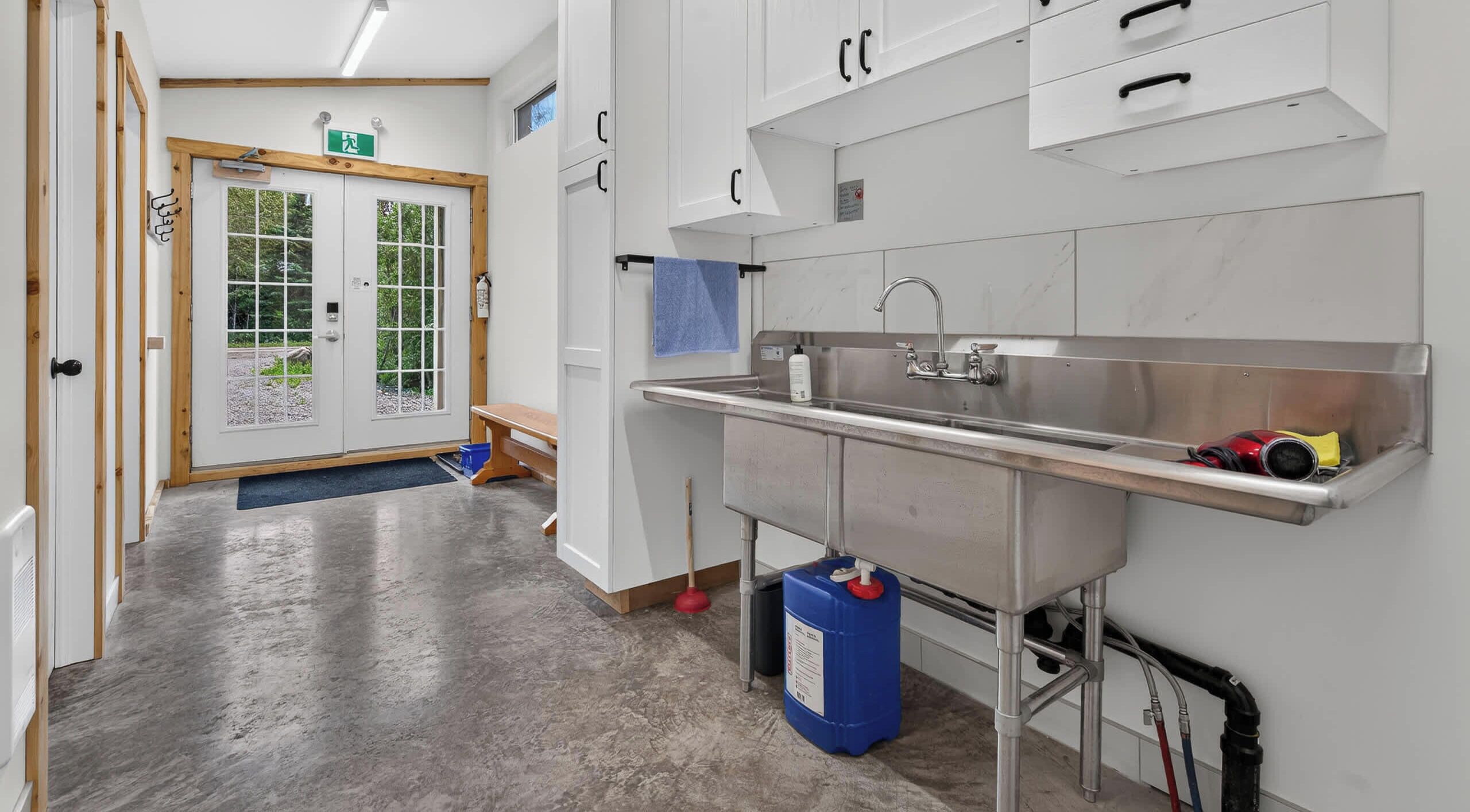 A clean, modern kitchen with stainless steel appliances, a sink, and a blue cleaning supply container.