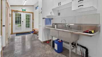 A clean, modern kitchen with stainless steel appliances, a sink, and a blue cleaning supply container.