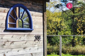 Une maison en bois avec une fenêtre bleue en arc de cercle et le numéro 2488 sur le côté.