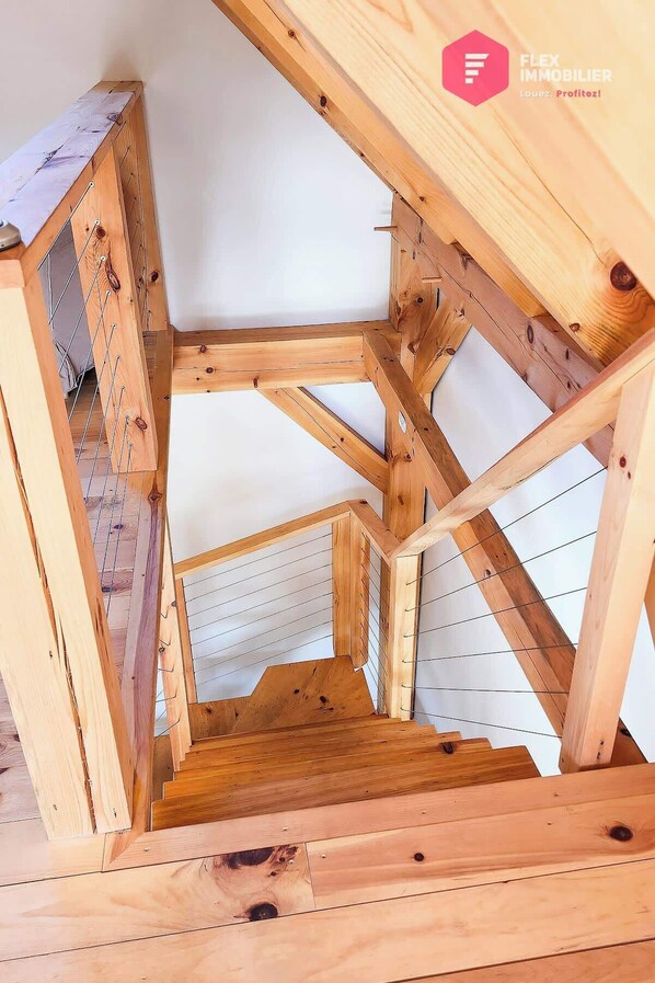 Une structure en bois située dans les combles, avec des poutres apparentes et un plafond en pente.
