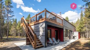 A modern cabin with a wooden deck, a staircase, and a red exterior wall. - The Singing Salmon of Bonaventure - A wild escape (Bonaventure)