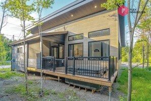 A modern mobile home with a covered porch, large windows, and a fenced deck area. - The Blue Pearl of Portneuf - Private hot tub Pool (Pont-Rouge)