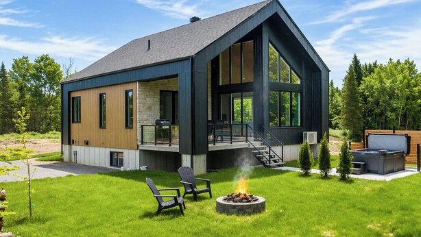 Une maison moderne dotée d’une grande terrasse, d’un foyer extérieur et de coins salon aménagés à l’extérieur.