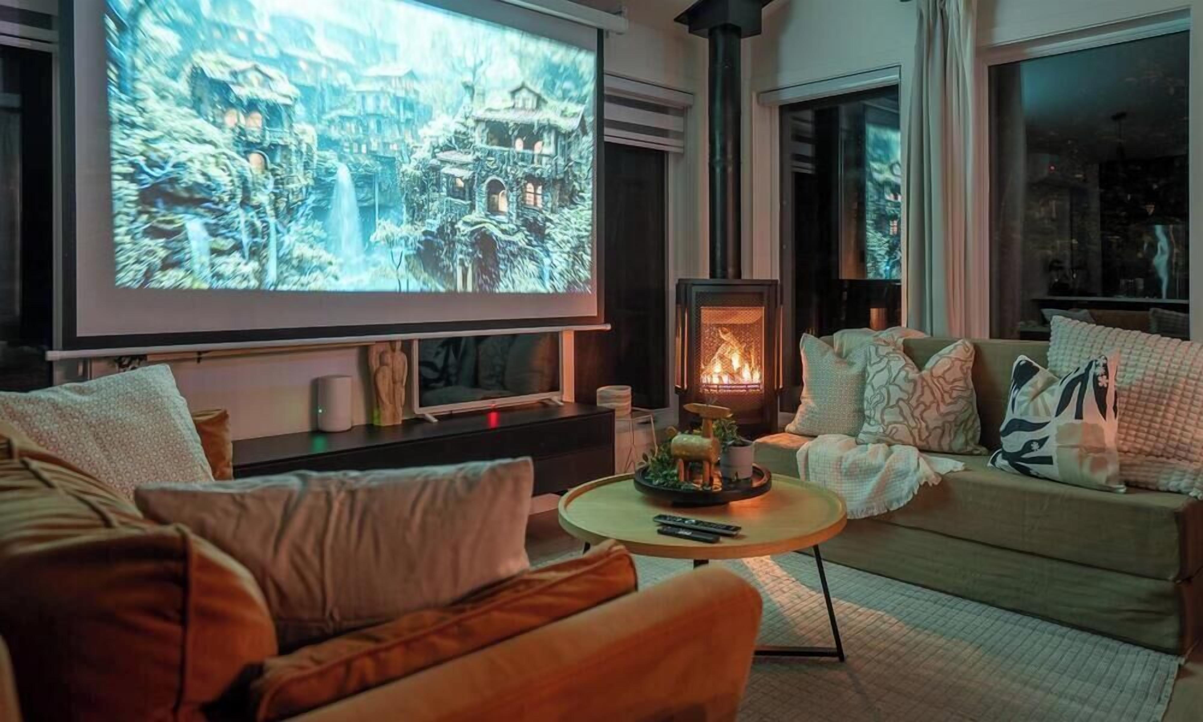 A cozy living room with a fireplace, a large screen for viewing, and comfortable seating.