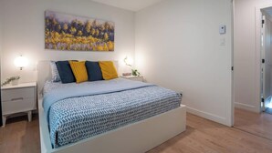 A bedroom with a bed, bedside tables, a wall-mounted light, and a door leading to another room. - King bed, Cinema screen, Private SPA, Near Quebec (Pont-Rouge)