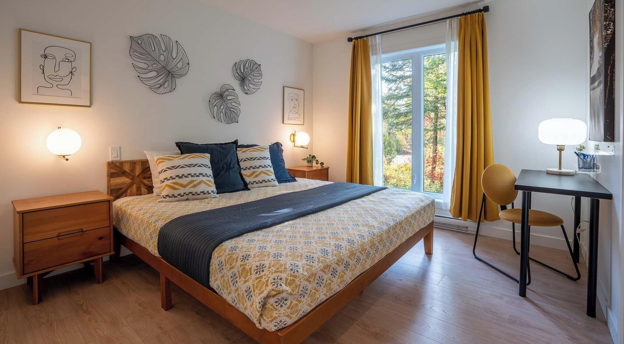 A bedroom with a bed, bedside tables, a desk, and a chair.