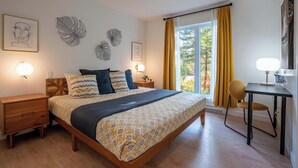 Un dormitorio con una cama, mesitas de noche, un escritorio y una silla.