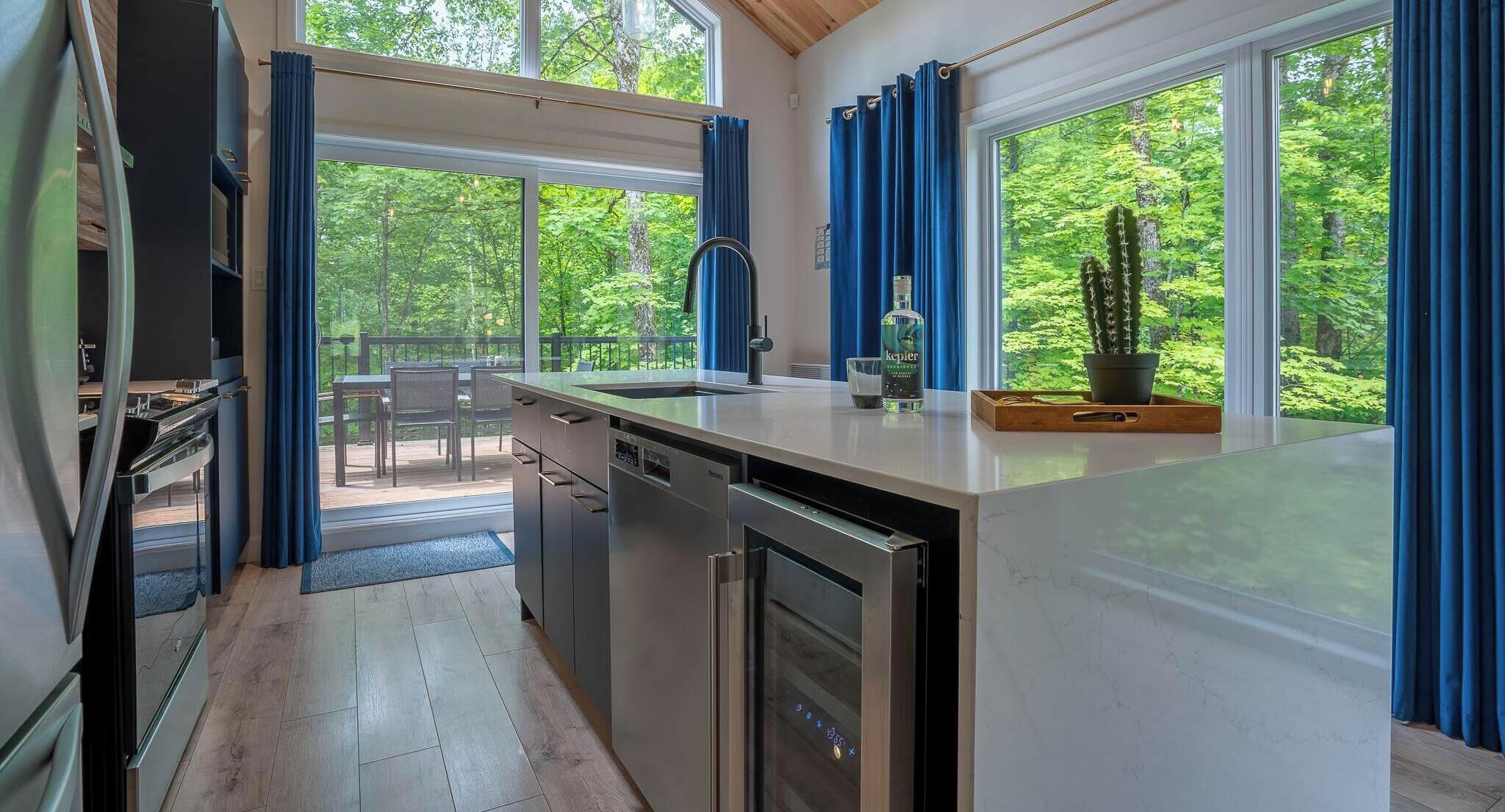 A modern kitchen with a view of a wooden deck and greenery.