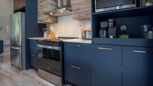 A modern kitchen with stainless steel appliances, wooden cabinetry, and a built-in oven. - The Bellevue in Portneuf - Private SPA, 65-inch TV (Pont-Rouge)