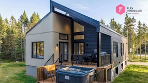 Une maison moderne à deux étages dotée d’une terrasse, d’un espace salon extérieur et d’un jacuzzi.