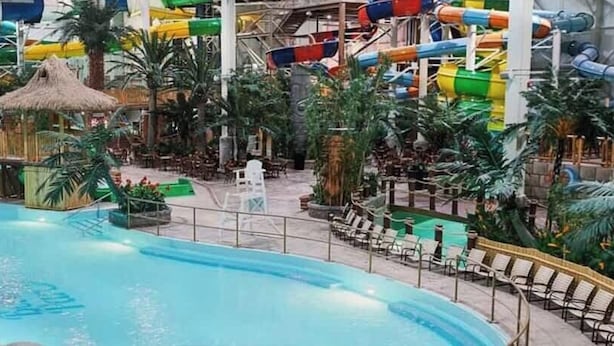 Un parc aquatique intérieur doté d’une grande piscine, de toboggans et de diverses structures de jeux aquatiques.