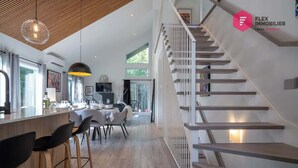 Un intérieur moderne comprenant un escalier, un coin repas et une cuisine.