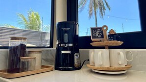 Ein Kaffeeangebot mit Kaffeemaschine, Tassen und einem Schild mit der Aufschrift 'Coffee Bar'.
