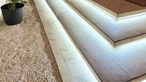 Ein Poolbereich im Freien bei Nacht mit Lichterketten, einer Betonplattform und Blumentöpfen.