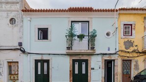 A row of buildings with distinct architectural styles, including a balcony with plants, a variety of door colors, and visible wear on the facades. - Cozy House B - By Y Concept (Setúbal)