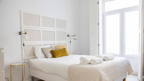 A neatly arranged bedroom with a bed, bedside lamps, and a window. - Setubal Downtown - By Y Concept (Setúbal)