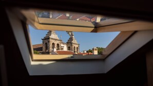 A view through a skylight of a building with two prominent towers and a cross. - Setubal Downtown - By Y Concept (Setúbal)