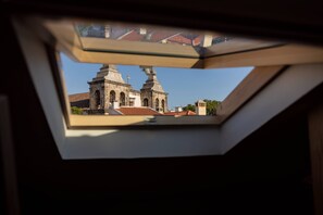 A view through a skylight of a building with two prominent towers and a cross. - Setubal Downtown - By Y Concept (Setúbal)