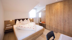 Un dormitorio con una cama de madera, una mesita de noche, un escritorio y un armario.