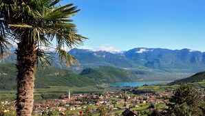 Un paisaje montañoso con un pueblo en el valle, rodeado de vegetación y un cielo azul despejado.