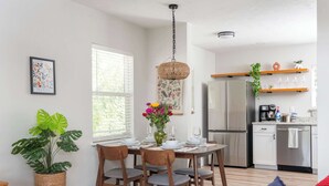 A dining area with a wooden table, chairs, and a hanging light fixture. - Serene Place, Walk to UF, Stadium, Near Shands & Downtown (Gainesville)