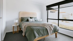A bedroom with a bed, a nightstand, a lamp, and a large window. - 2 Houses, Sleeps 12, 4 Bathrooms, Private Location (Sale)