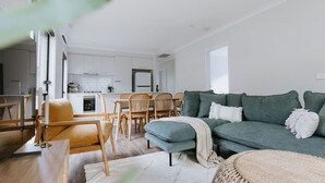 A modern living room with a green sofa, wooden dining table, and chairs. - 2 Houses, Sleeps 12, 4 Bathrooms, Private Location (Sale)
