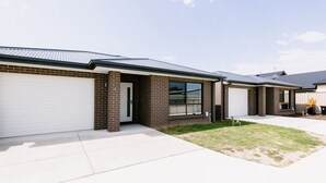 A row of modern houses with brick facades and white garage doors. - 2 Houses, Sleeps 12, 4 Bathrooms, Private Location (Sale)