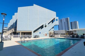 Un bâtiment moderne doté d’une piscine, d’un espace extérieur aménagé et d’un escalier menant à un niveau supérieur.